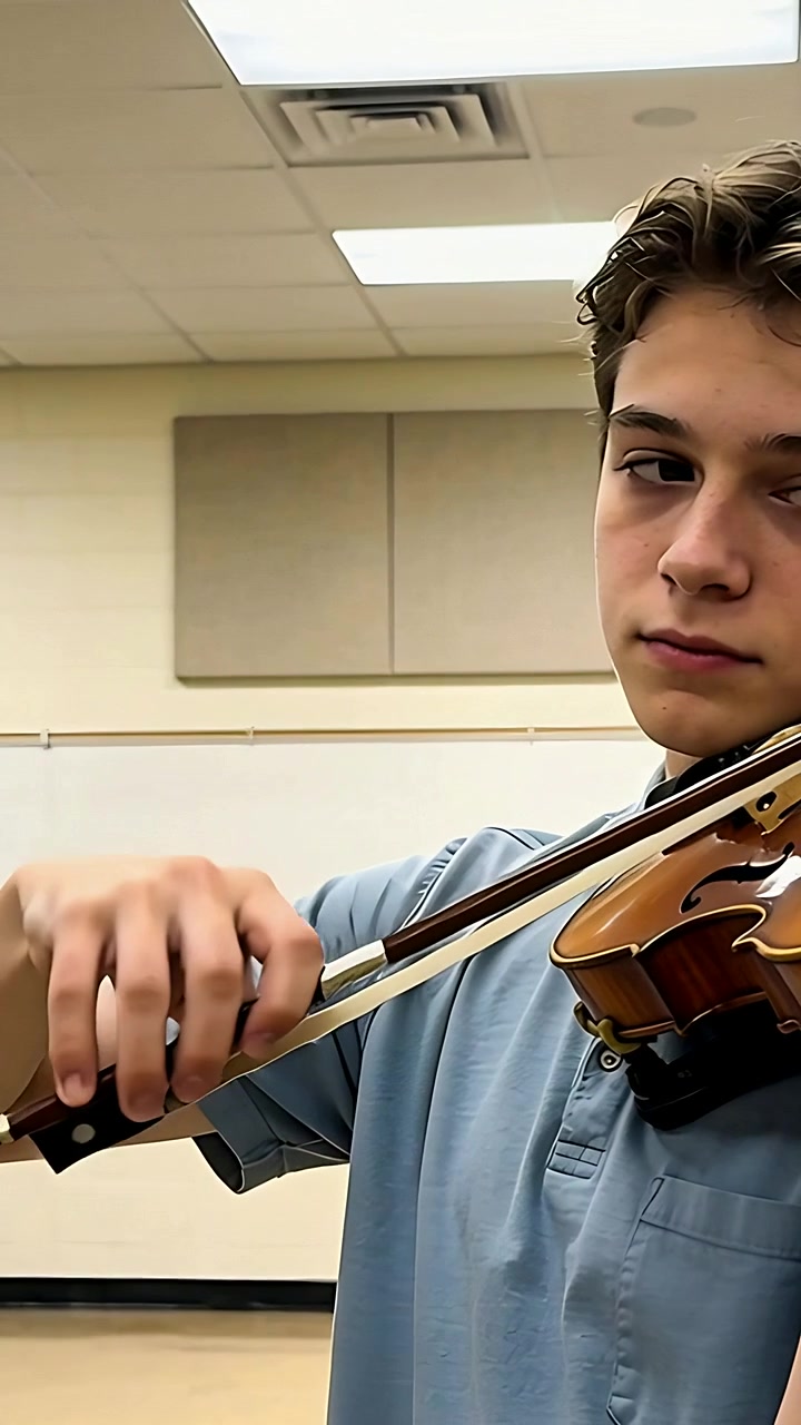 Vertical video: Camera starting violinist practicing on violin in music room blue polo, copy space