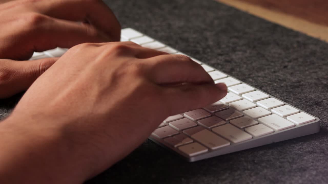 Male latino hands typing fast ina white wireless keyboard using all his fingers