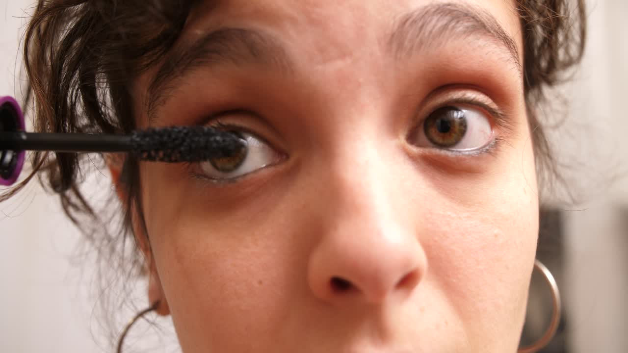 Close-up de jovem mulher aplicando rímel nos cílios
