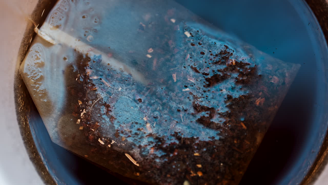 Close up of a tea bag brewing into a red cup