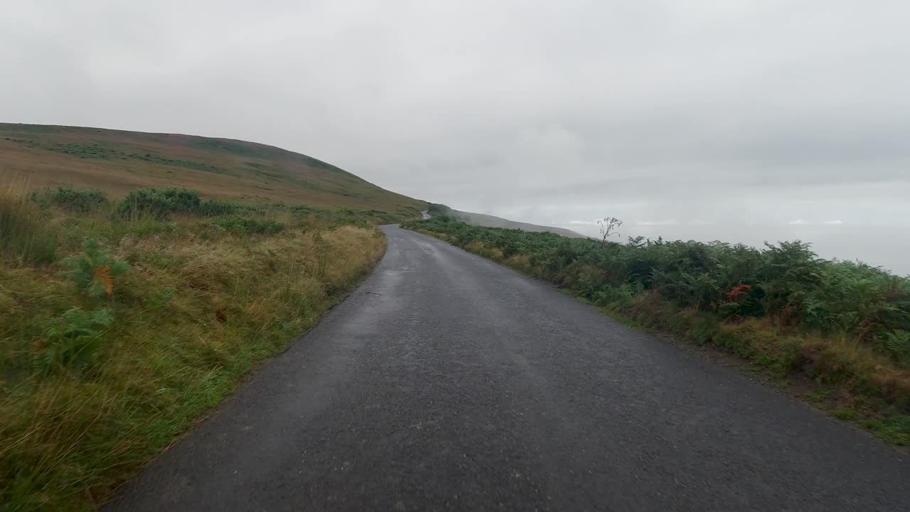 Driving POV on Countryside Road with Fog and Mist on Overcast Day with Moorland Peak and Green Landscape in North Devon UK 4K