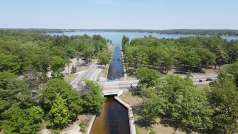 Small-boats-crossing-between-lakes-on-small-canal-in-Micihgan,-aerial-view