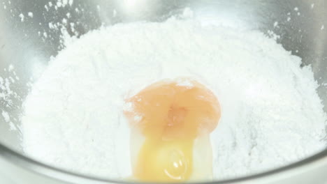 close-up of egg being added on flour