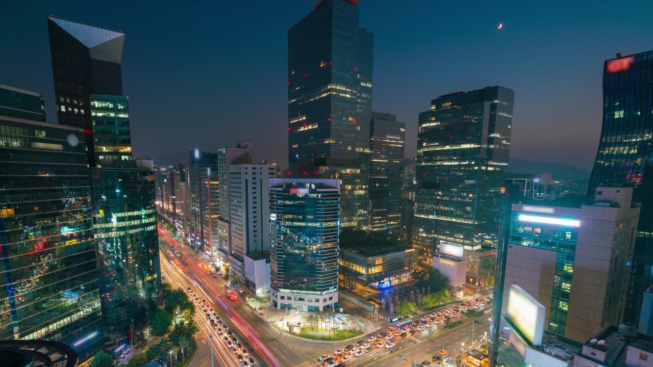 timelapse día a noche al atardecer de los senderos de luz la velocidad del tráfico a través de una intersección en el distrito comercial de gangnam center de seúl en la ciudad de seúl, corea del sur.