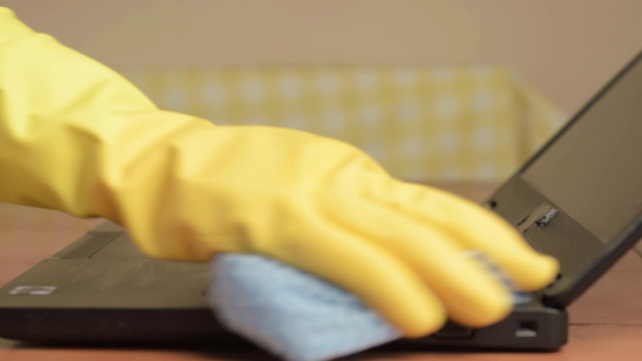 Hands in rubber gloves cleaning laptop with cloth close up shot