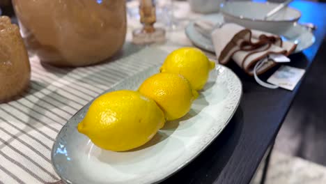 close up shot of yellow lemons on plate on decorated table at home