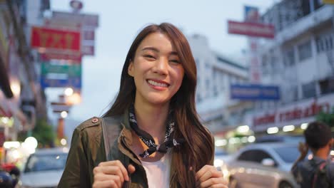 밤에는 도시 거리에서 웃는 여성 여행자