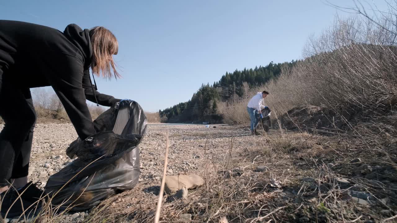 команда очищает пластик на пляже. добровольцы собирают мусор в мусорный мешок. загрязнение пластиком и концепция экологической проблемы. доброволная очистка природы от пластика. озеленение планеты