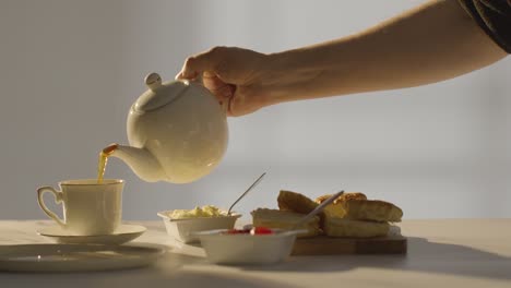 fotografía de estudio de una persona con el tradicional té de la tarde británico con crema de bollos y mermelada 2