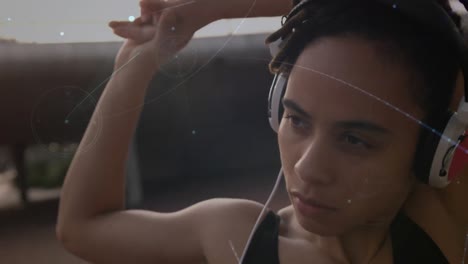 red de conexiones contra afroamericana mujer en forma con auriculares estirando sus brazos