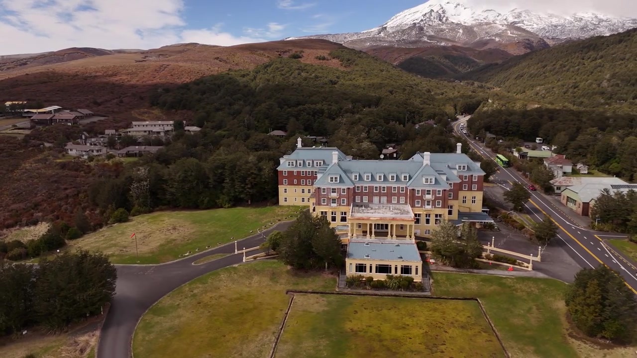 Yeni Zelanda, Tongariro Milli Parkı'nda, karla kaplı dağ zirvesiyle Chateau Tongariro Tarihi Oteli.