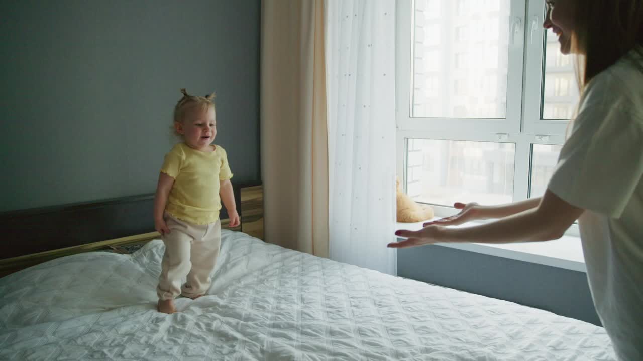 Happy Baby Girl Playing with Mother on Bed at Home