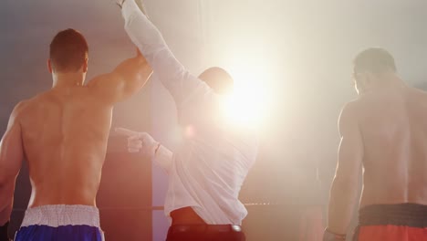boxeador sosteniendo la mano del ganador después de anunciar la victoria