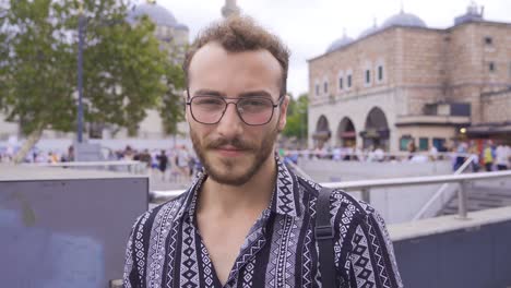 young man dealing with phone looks at camera.