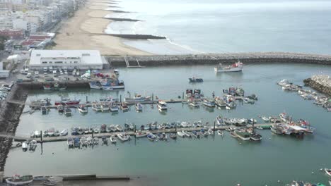 Drone-flies-over-quarteira-port-Marina-in-Portugal-with-tilt-up-revealing-sandy-beach-in-the-background,-Aerial-Flyover