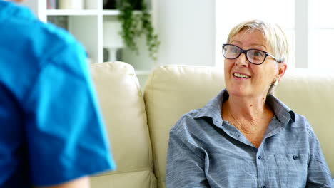 Senior-old-woman-sitting-on-couch-in-nursing-home-talking-with-the-doctor