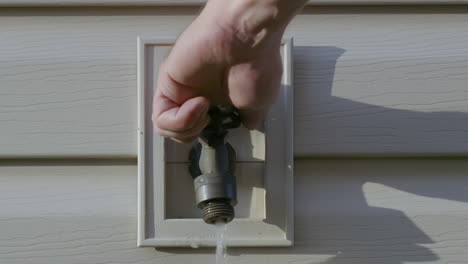 white adult, male, left hand turning handle of freshwater spigot until water flows out