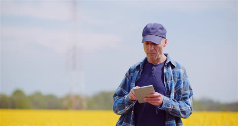 farmer examining agricultural field while working on digital tablet computer at farm 7