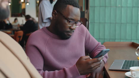 black businessman using smartphone in cafe