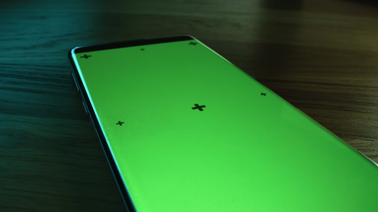 Primo piano macro con telecamera che vola sopra uno smartphone moderno con schermo mock-up verde acceso. Telefono cellulare con display Chroma Key. Punti di tracciamento del movimento per un facile utilizzo.