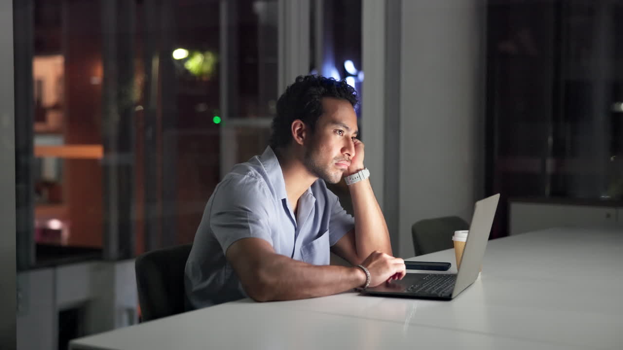 Tired Man Working Late on Laptop in Modern Office at Night