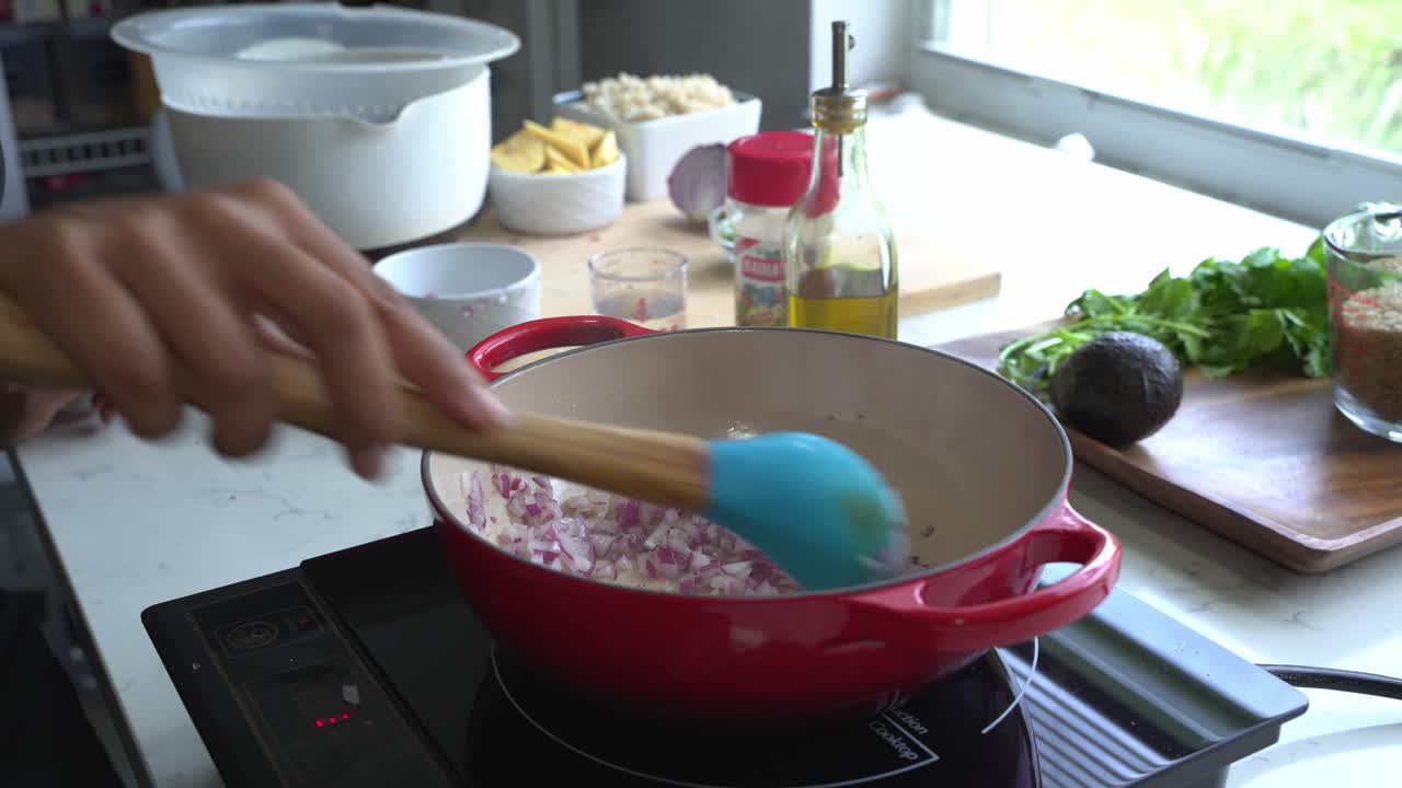 agitar cebollas rojas en una sartén e ingredientes especiales para cocinar una comida dos latas de frijoles arroz plátano aguacate cebolla roja y cilantro