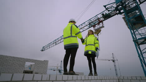 foreman and civil engineer are discussing construction project in building site man and woman are shaking hands