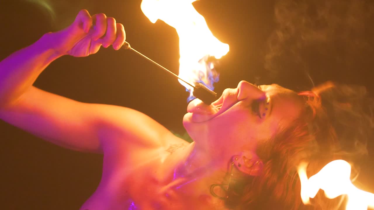 Slow motion di una bella mangiafuoco che spegne la fiamma nella sua bocca