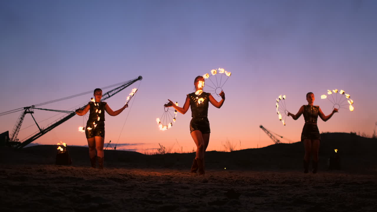 fuego muestran tres mujeres en sus manos girar lanzas ardientes y ventiladores en la arena con un hombre con dos lanzallamas en cámara lenta