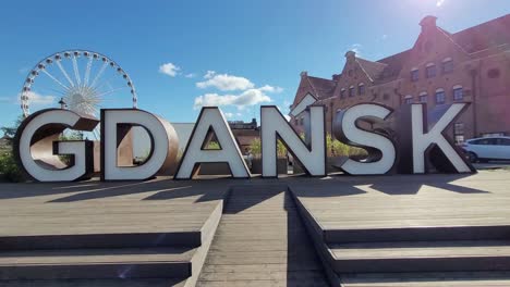 sign of the city of gdansk with the ferris wheel behind