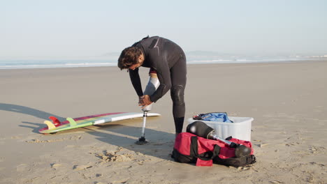 surfista masculino con discapacidad grabando una pierna artificial en la costa