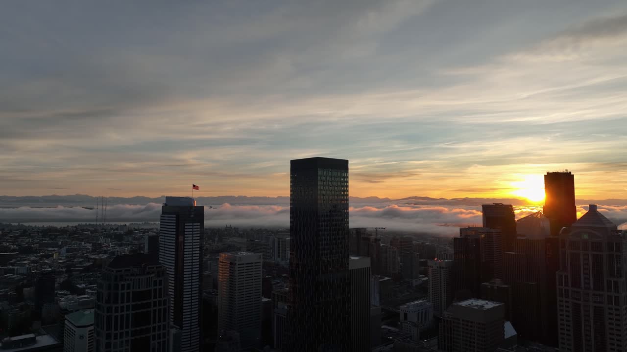 Vista del amanecer del horizonte de la ciudad de Seattle con un atardecer dorado sobre nubes ondulantes.