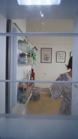 woman looking inside refrigerator