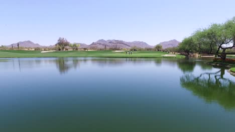 several golfers walk up to green across from water hazard at greyhawk golf course, scottsdale, arizona