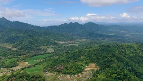 drone flying over verdant valley with menoreh hills in background, muntilan in indonesia