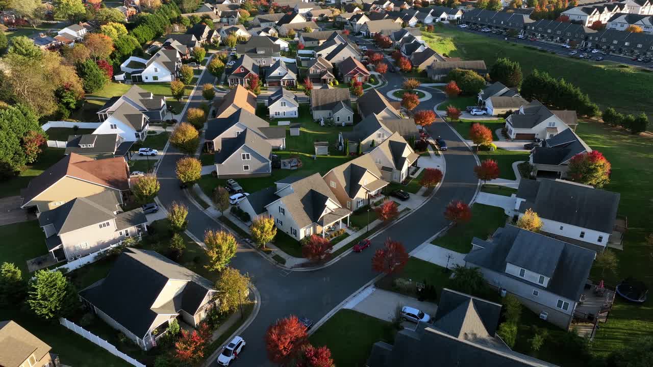 Modern style architecture homes in quiet neighborhood of USA. Aerial orbit top down. Sunny day with colorful trees in fall. Luxury one family houses in suburbia. Expensive real estate Buildings.