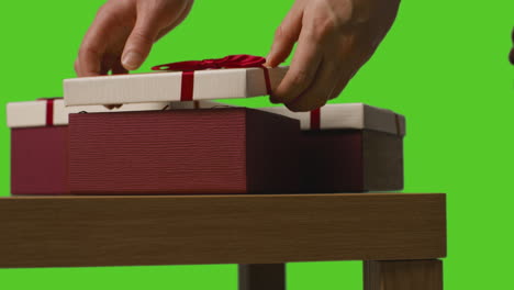 close up of man opening gift wrapped present on table shot against green screen 1