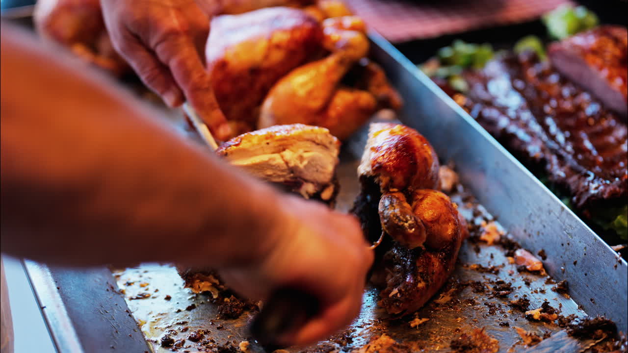 Close up of a man cutting up grilled chickens at a food stand