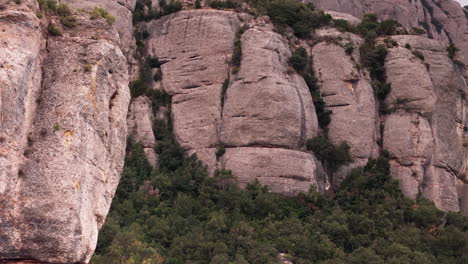 uma tomada de um guindaste de drone revelando graciosamente os picos redondos das falésias de montserrat contra o pano de fundo de um dia nublado e tranquilo.