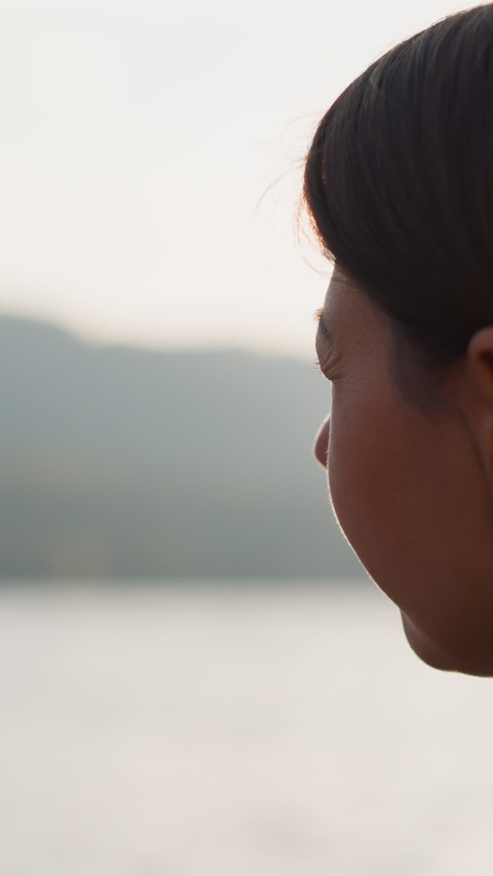 dama lanza piedras al lago en un día soleado. relajación al pasar tiempo en la naturaleza con impresionantes vistas de las montañas en otoño. momentos tristes de la vida solitaria