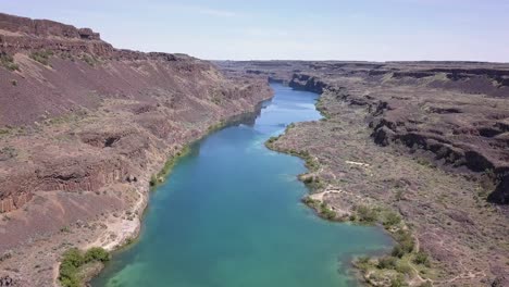 aerial descends over dramatic rocky sagebrush landscape, deep lake wa