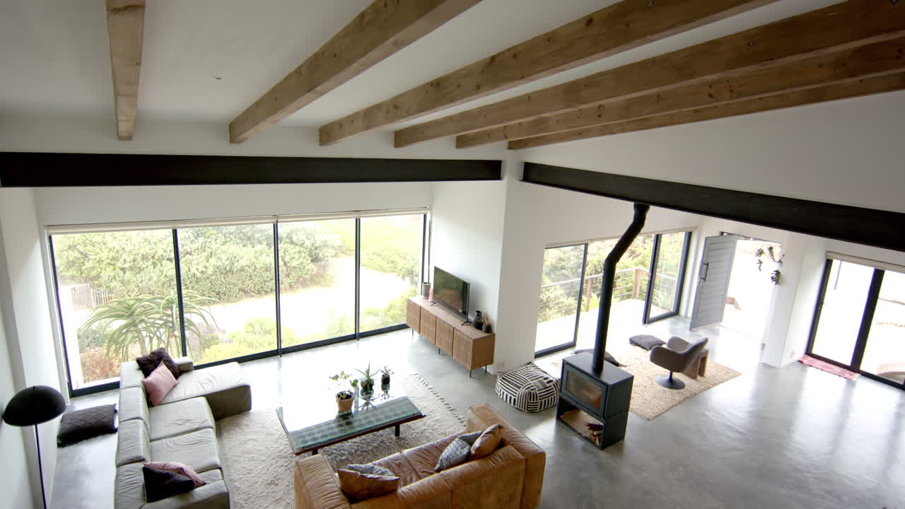 Modern living room with large windows, cozy furniture, and wooden beams