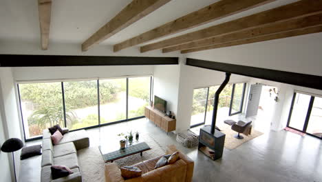 modern living room with large windows, cozy furniture, and wooden beams