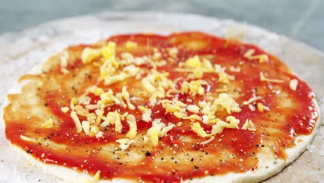 esparciendo aderezos de queso en la base de la pizza