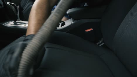 Close-up-of-a-male-wearing-black-gloves-vacuum-an-black-interior-car