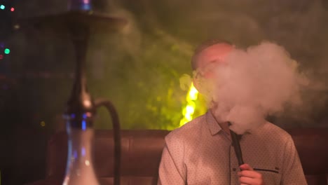 man smoking hookah in a night club