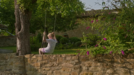 Woman-on-tree-swing-enjoys-peaceful-solitude-of-garden-on-summer-morning