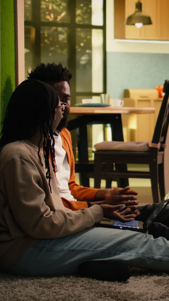 Vertical Video African American couple solving remote tasks together on the floor