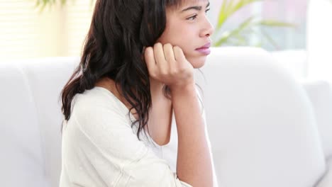 mujer estresada sosteniendo su cabeza en el sofá