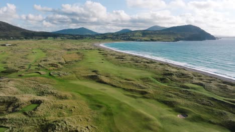 aerial flyover of green rolling fairways on coastal links golf course in ireland